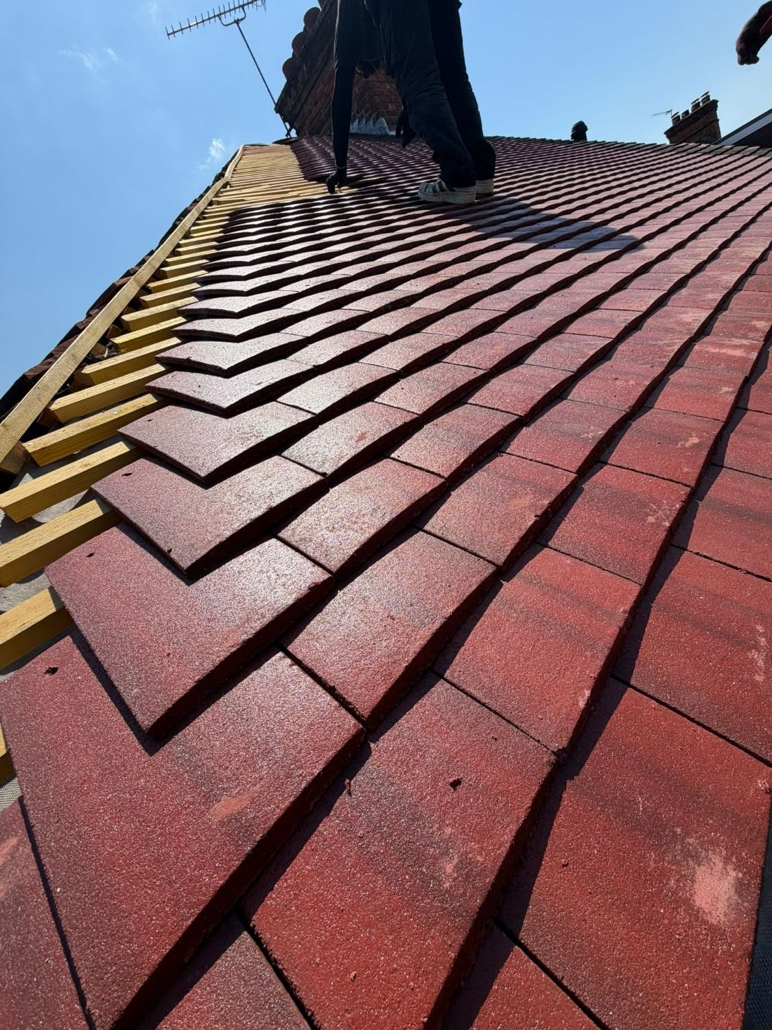 Close-up of new red tiles being laid on fresh battens