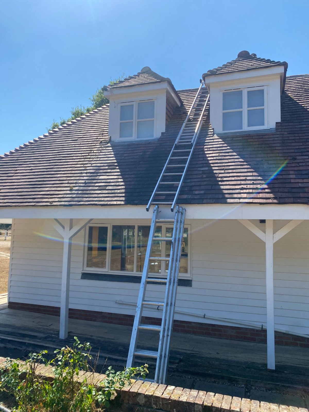 Ladder up to two dormer windows on a tiled roof