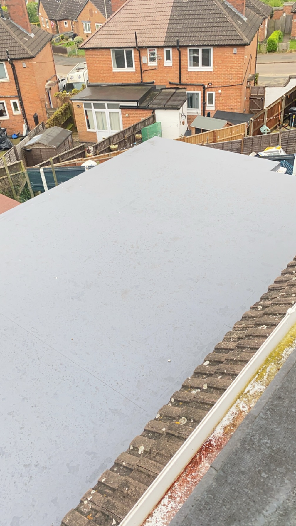 Wide grey single ply flat roof on a rear extension, overlooking neighbouring gardens