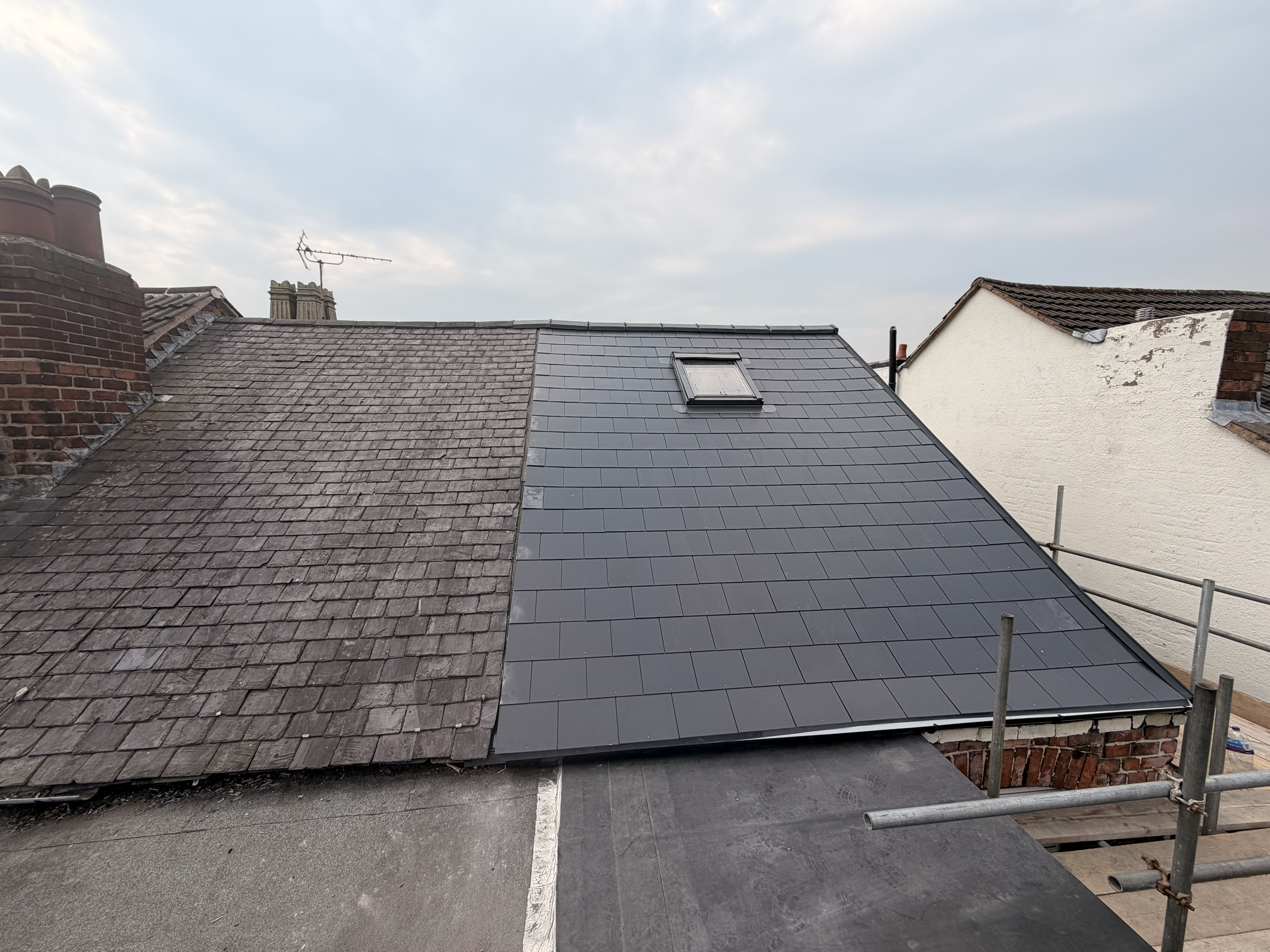 Pitched roof seen from scaffolding, showing straight courses of tiles and a clean verge