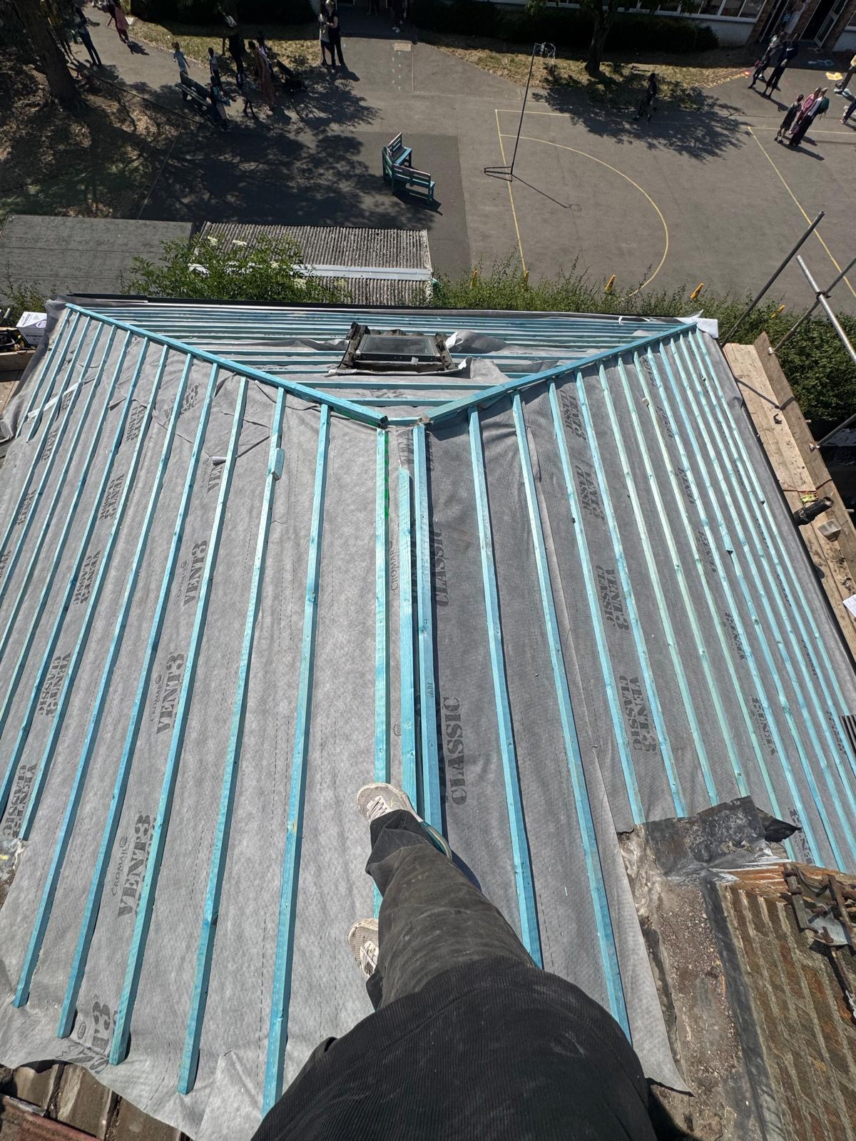 Scaffolding standing against a house with the roof stripped back to the timbers