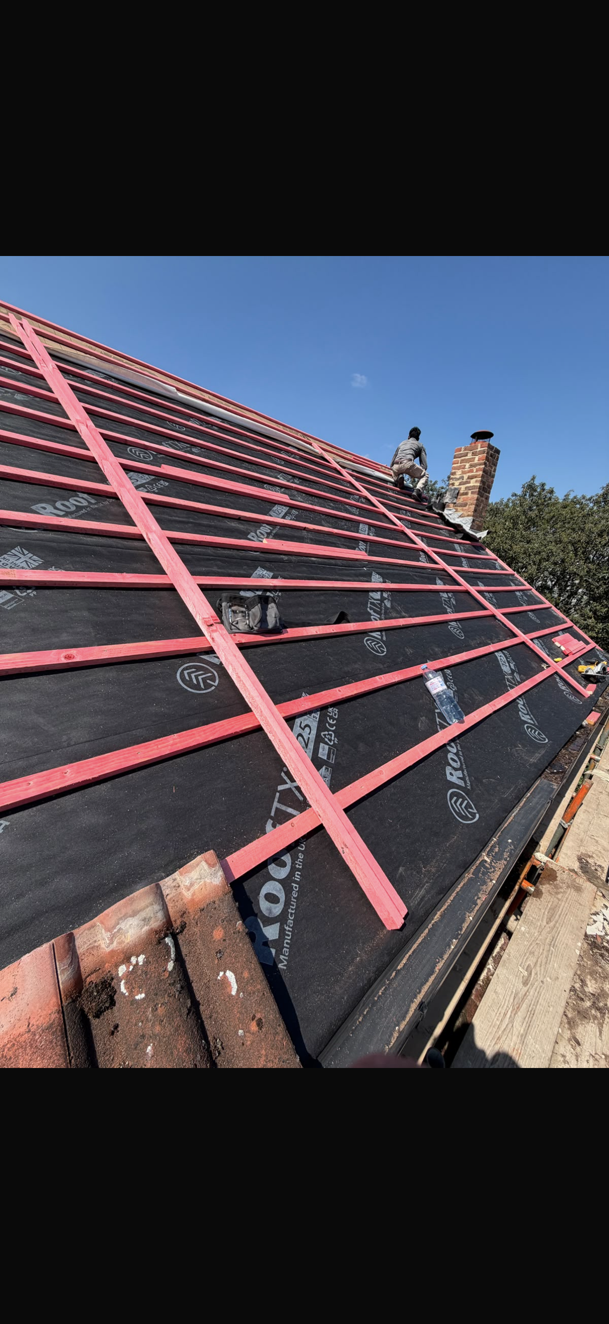 Roof stripped to the rafters with old insulation visible between them