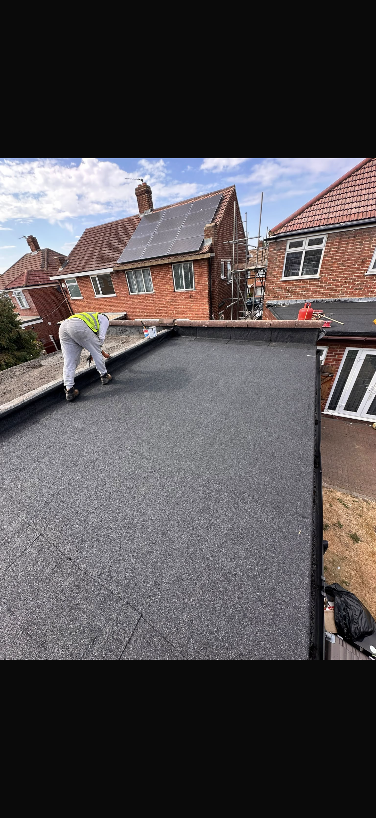 Completed dark grey tiled roof with ridge and hip tiles bedded in