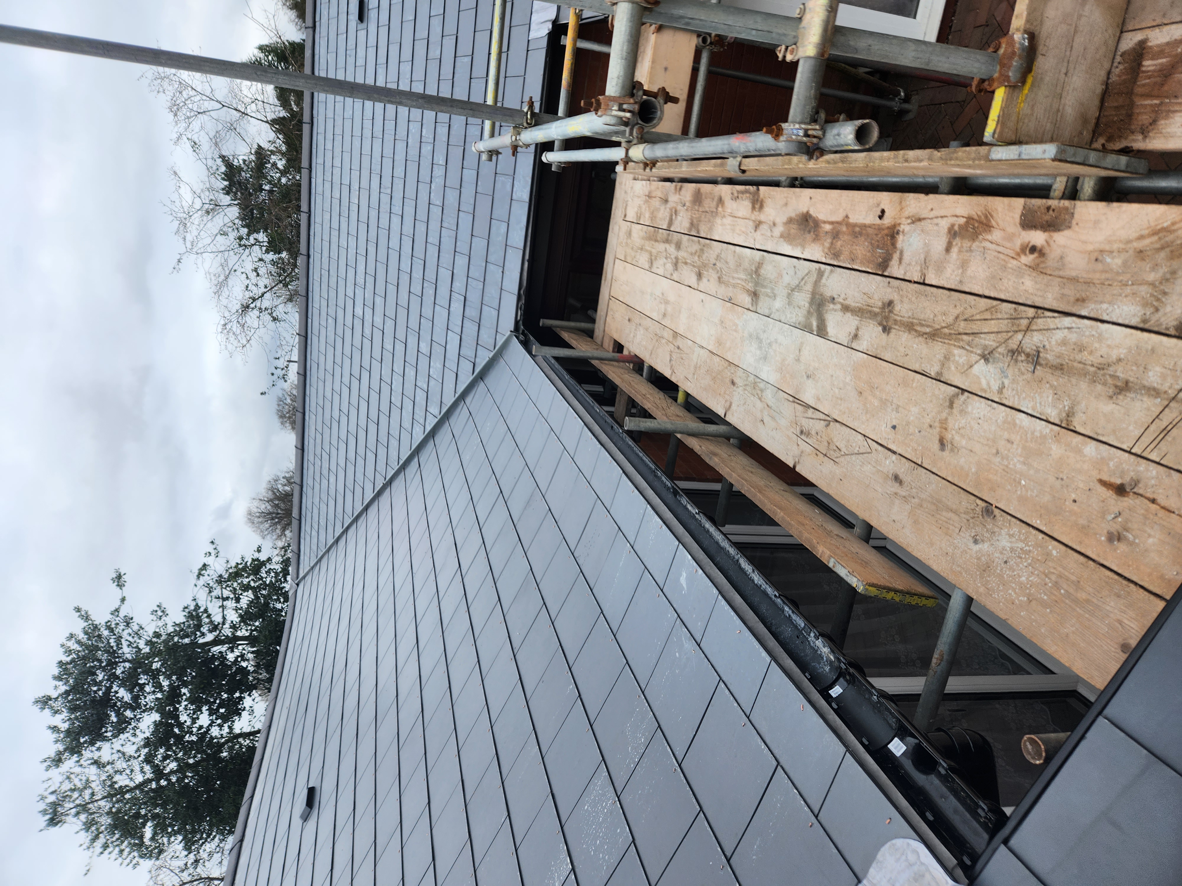 Freshly slated pitched roof seen from scaffolding, with new lead valley