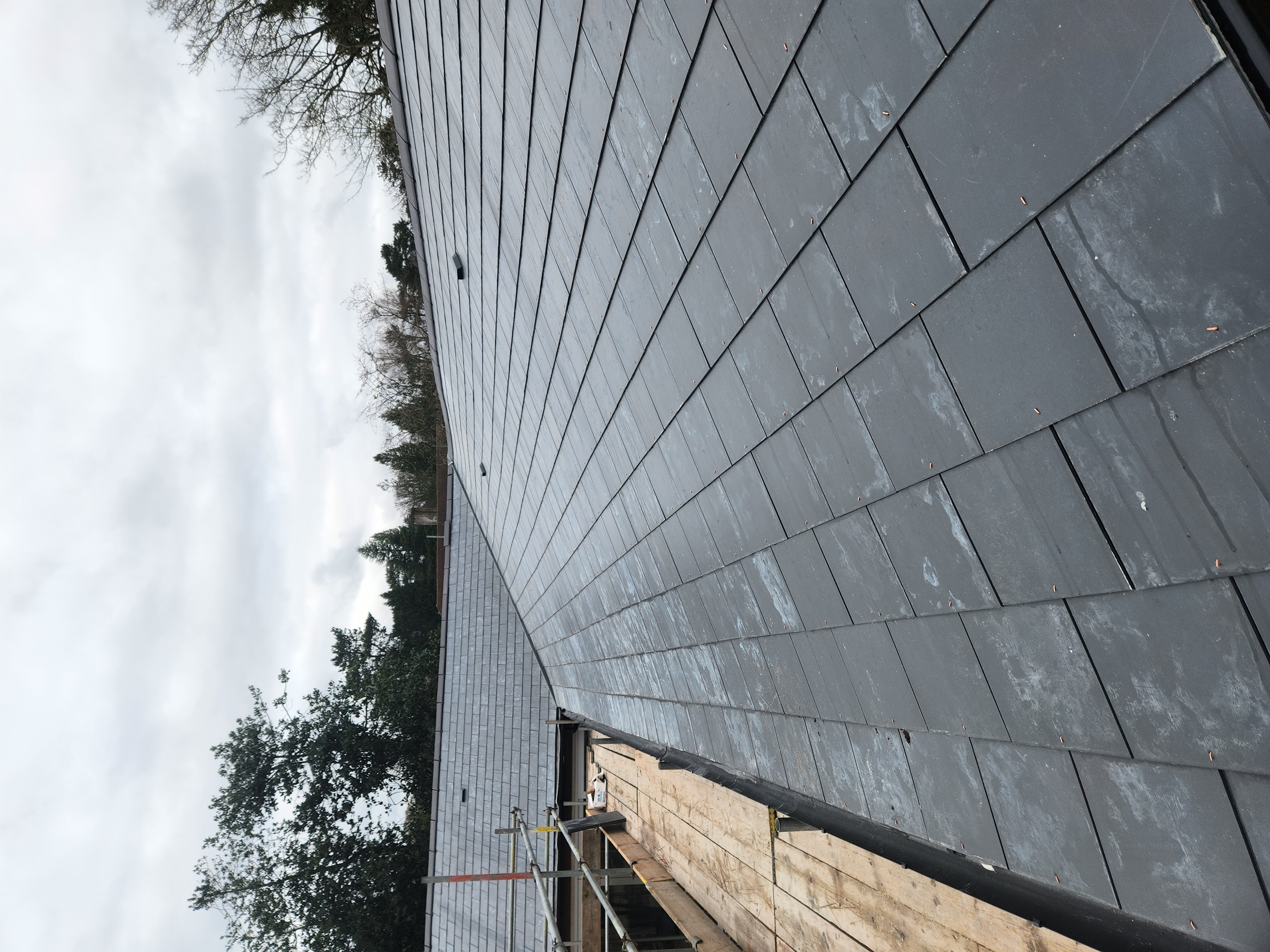 Slate roof slope beside scaffolding boards on a residential property