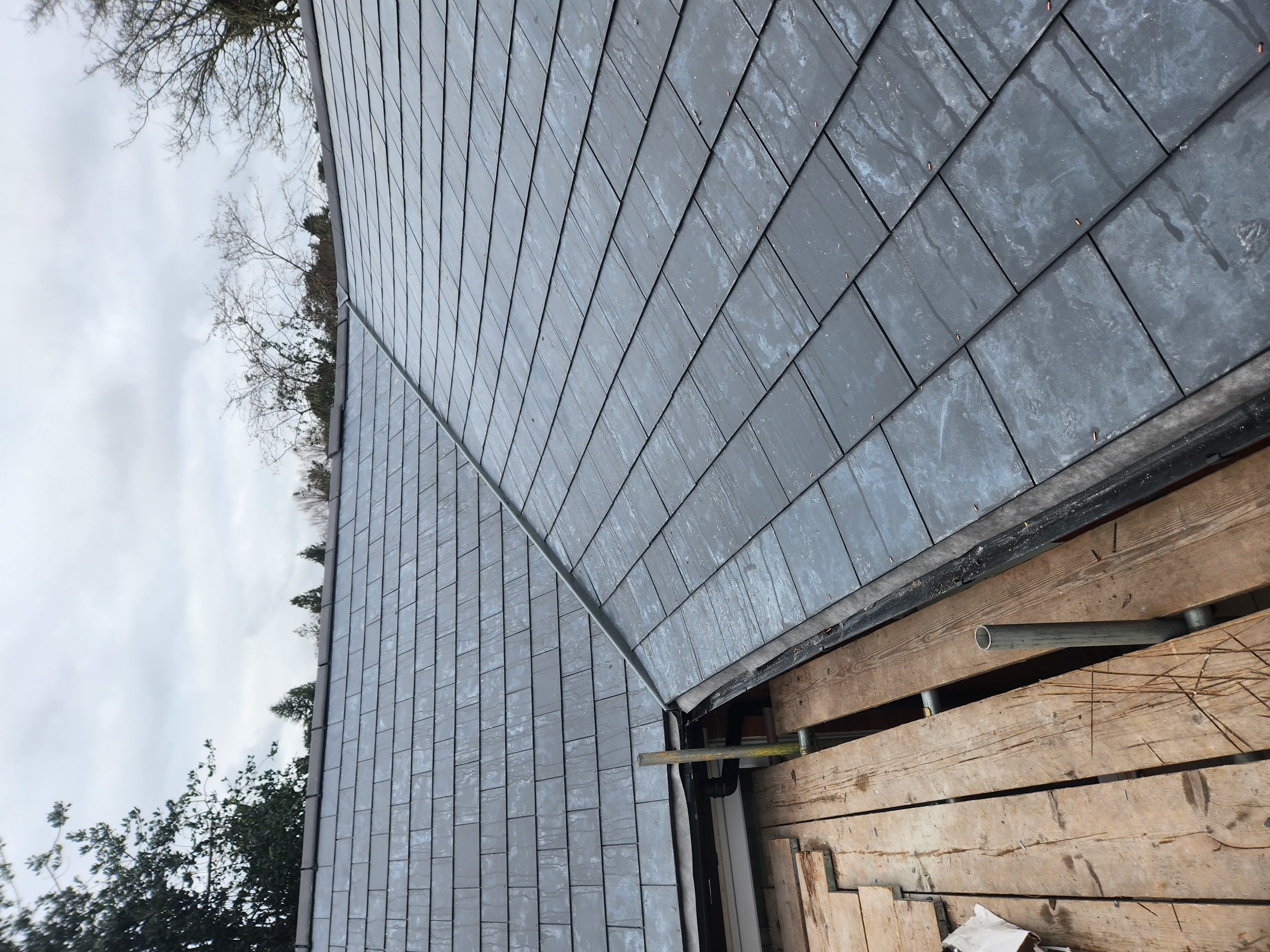 Newly completed slate roof with black fascia and guttering