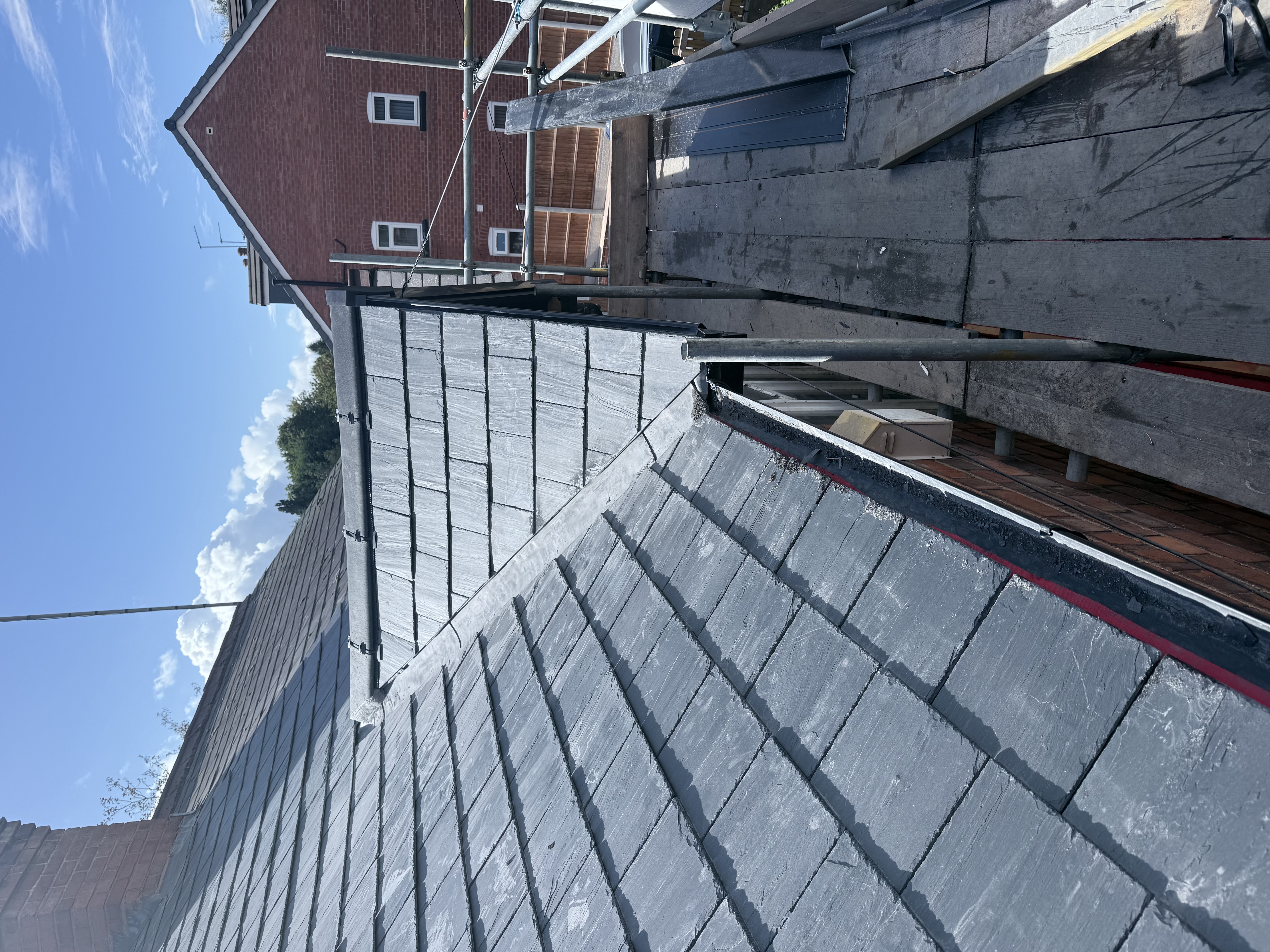 Grey tiled roof finished on a house with scaffolding still up