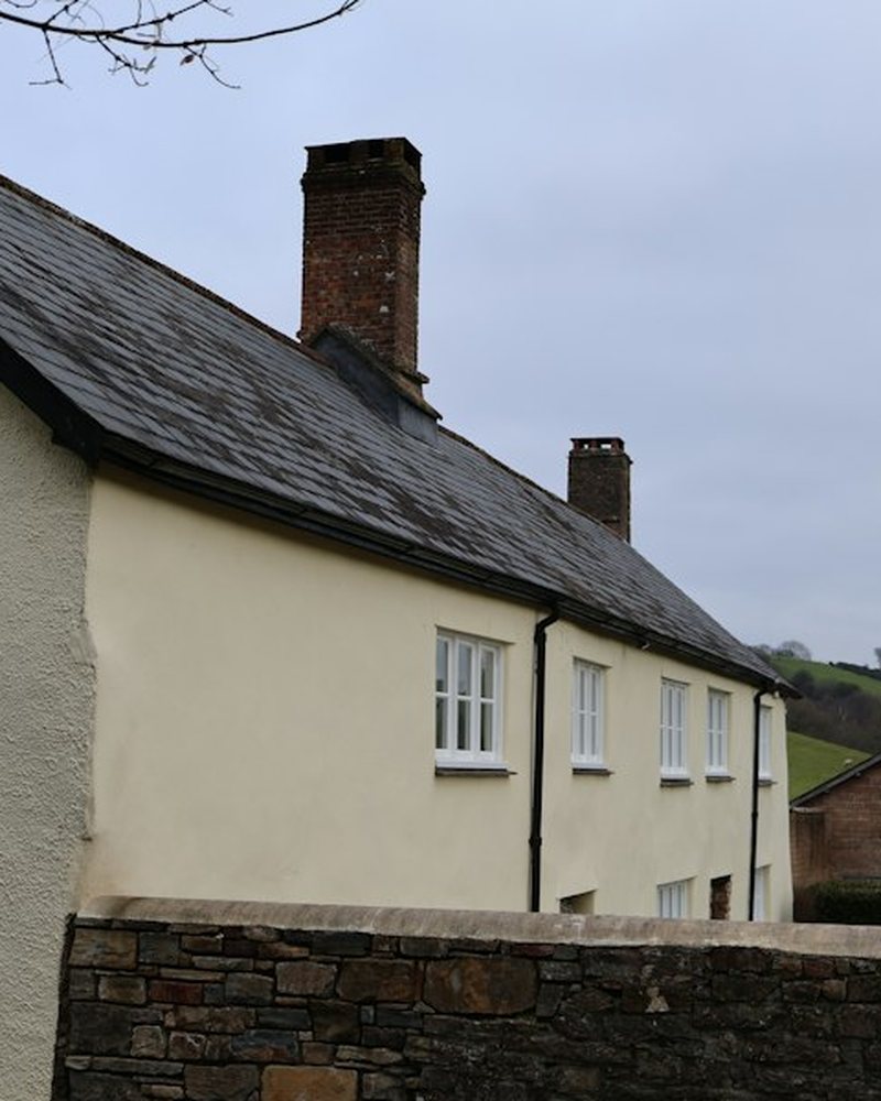 Cream rendered cottage with a slate roof and brick chimney