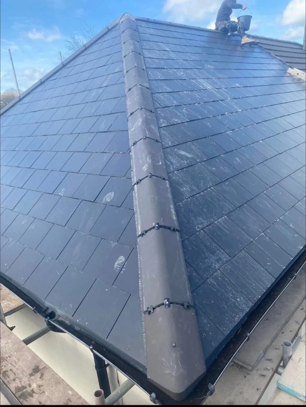 Close view of a newly tiled hipped roof with dark flat tiles and bedded ridge tiles