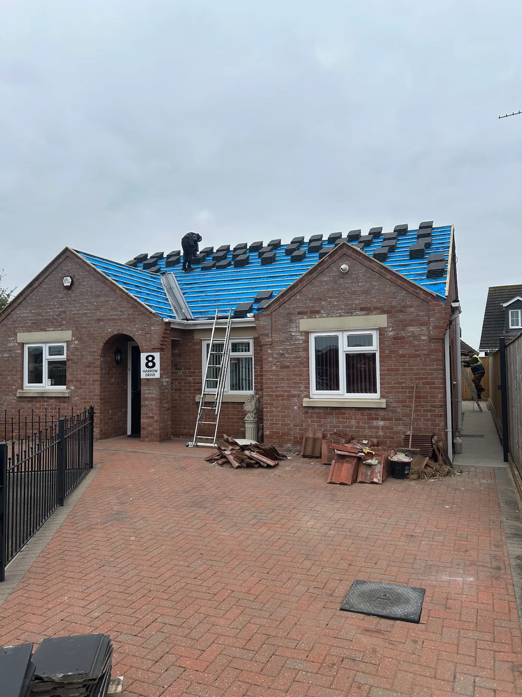 Bungalow part way through a re-roof, blue breather membrane and battens exposed with a ladder up