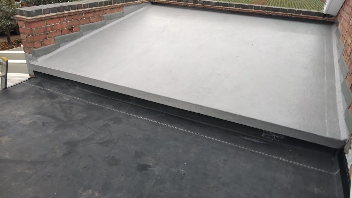 Grey single-ply flat roof membrane dressed up an upstand against a brick wall