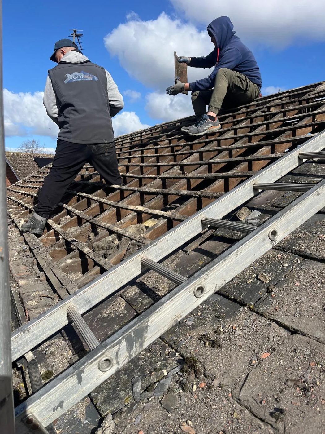 Roofers stripping an old roof back to the timber battens