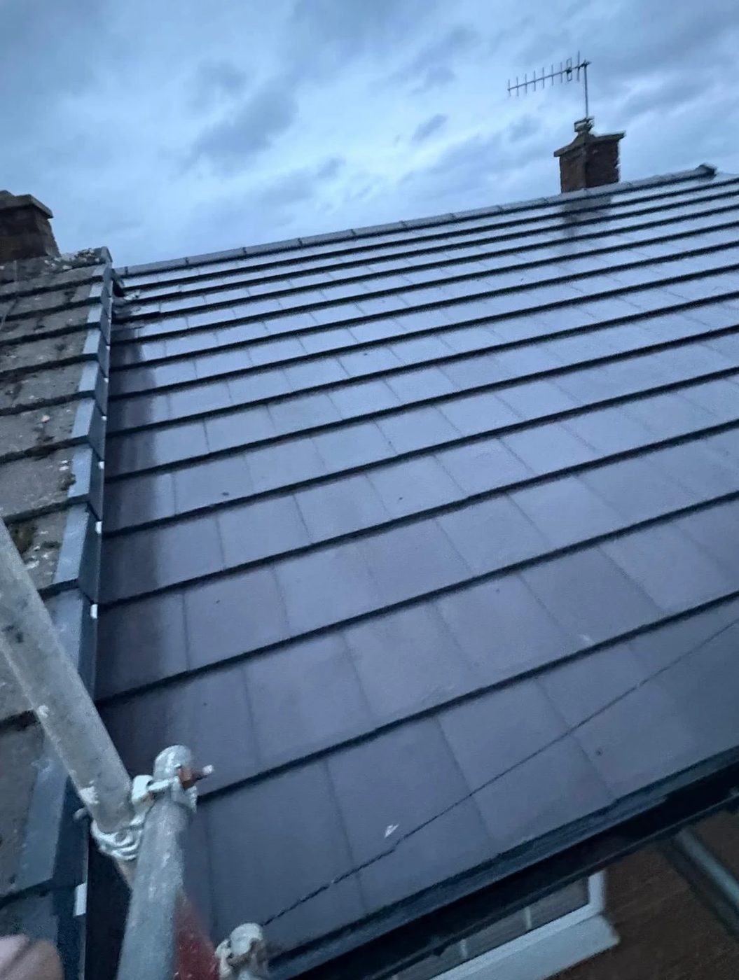 Completed dark tiled roof with scaffolding still in place