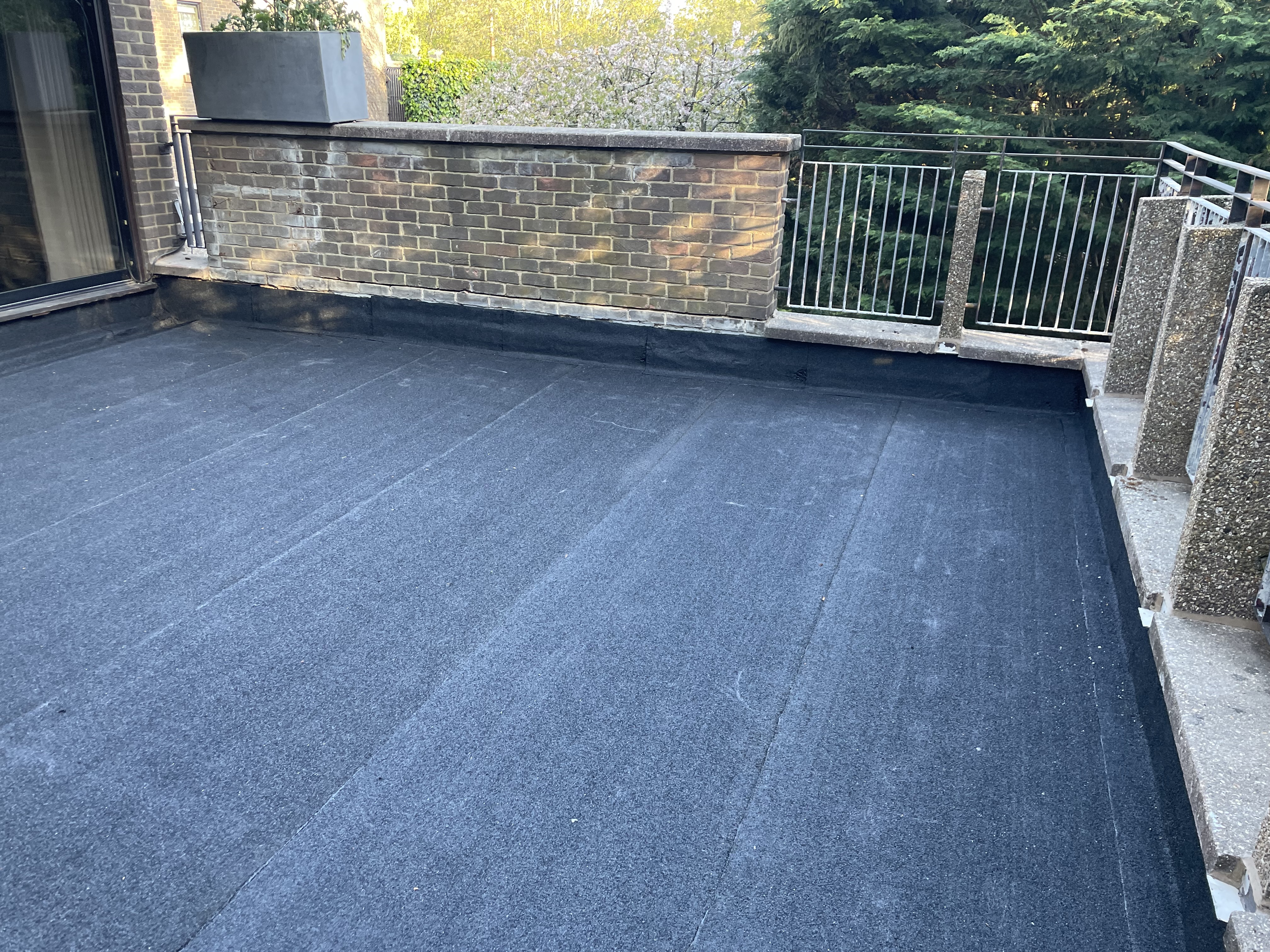 Finished slate roof and guttering seen from scaffolding, with rooftops behind