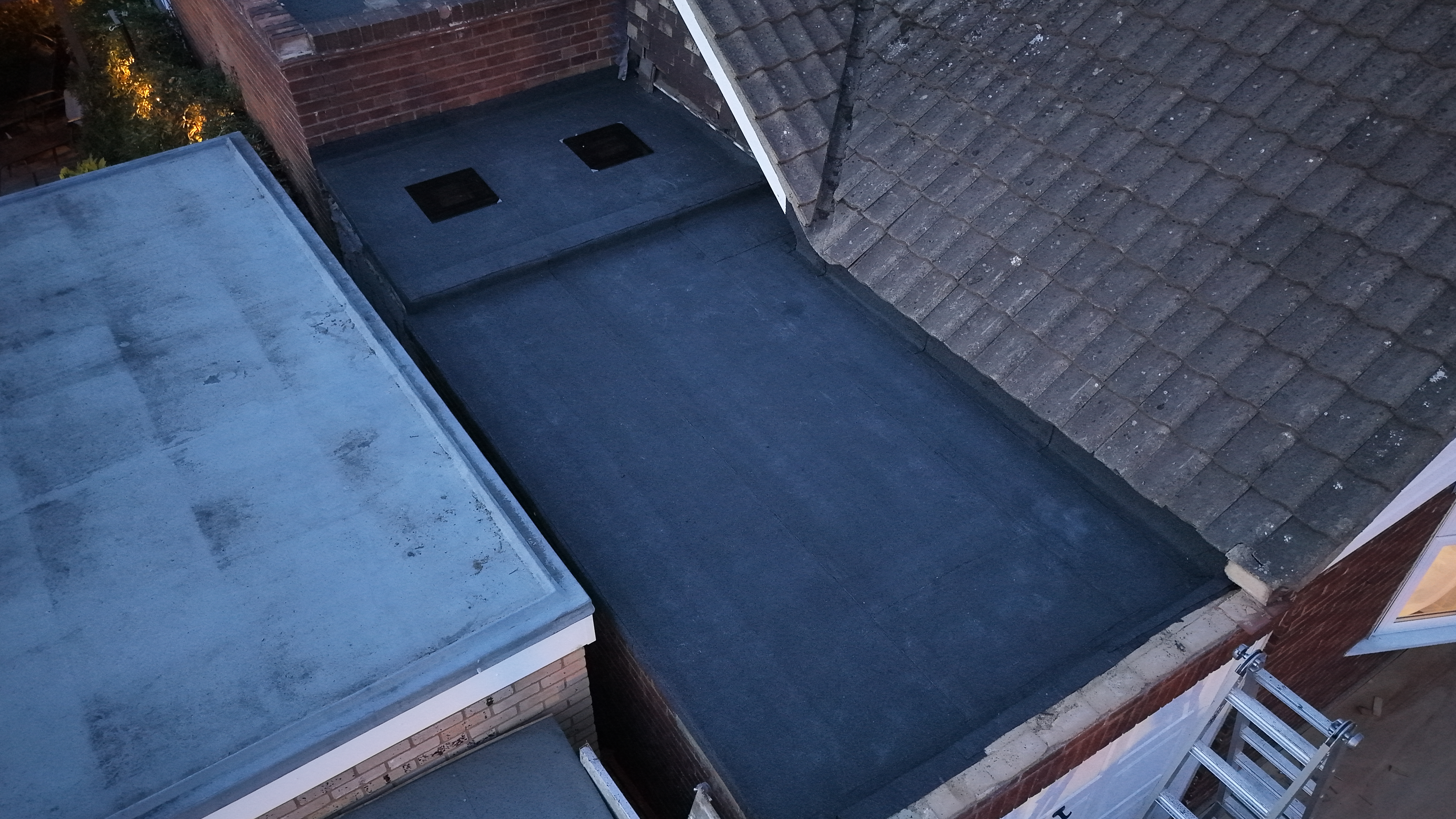 Aerial view of a finished house roof with dormers, scaffolding still in place around the property