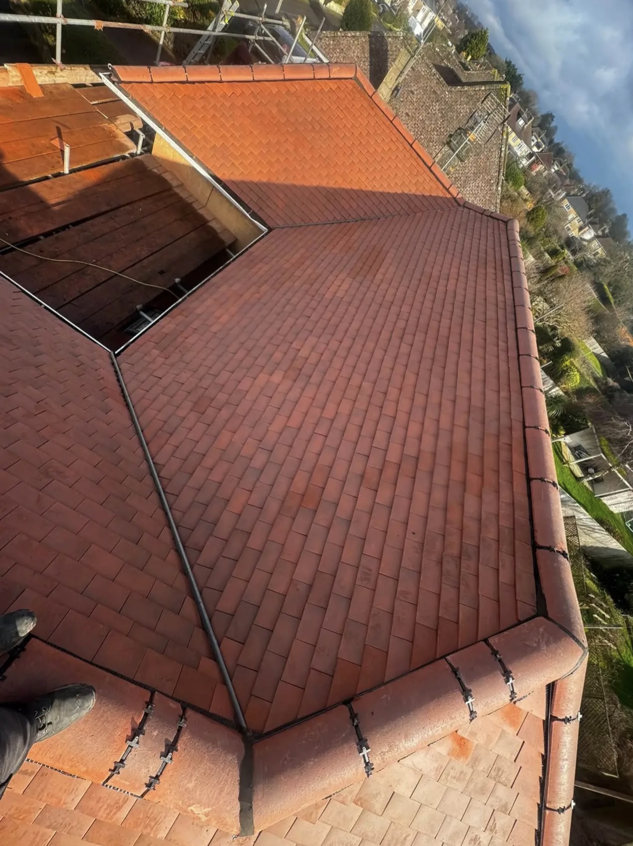 Red tiled hipped roof seen from above, with lead-lined valleys running down to the gutters