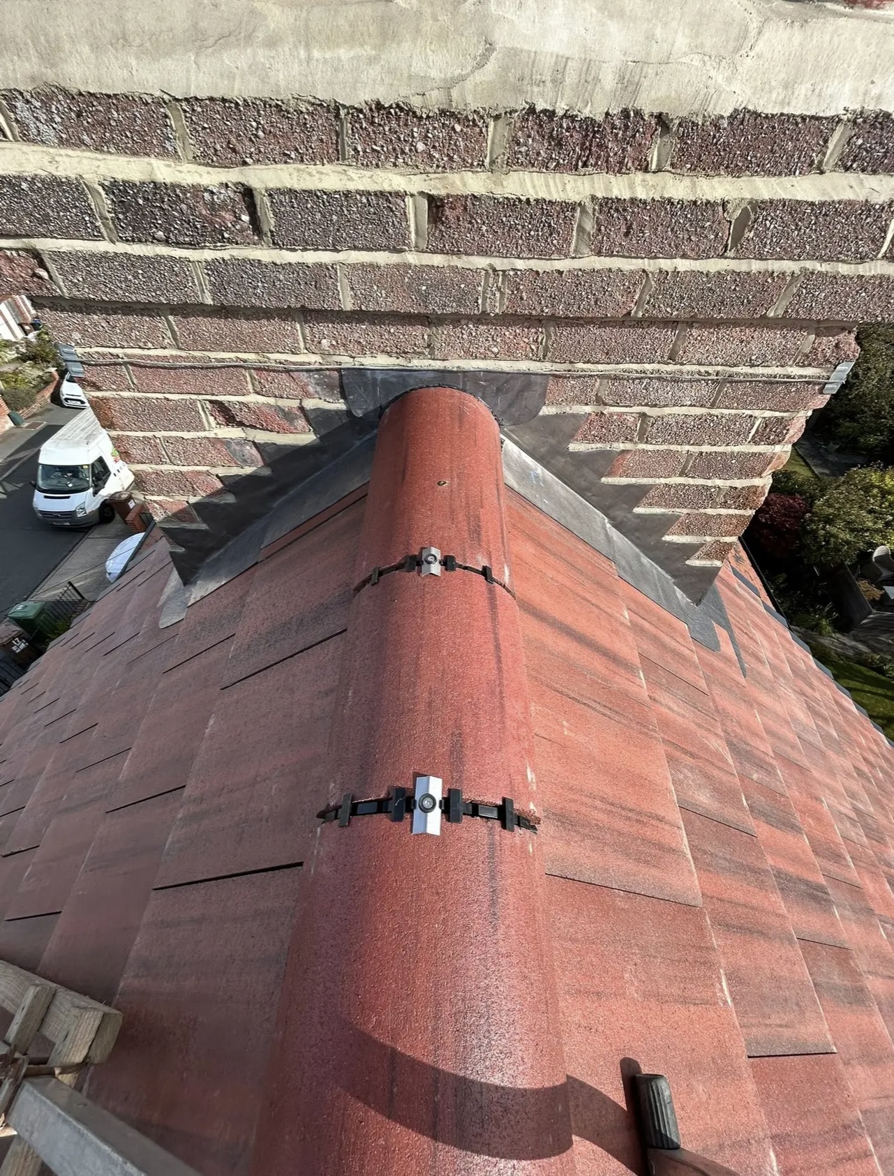 Red tiles taken up to a hip, with the brickwork of the chimney stack rising behind