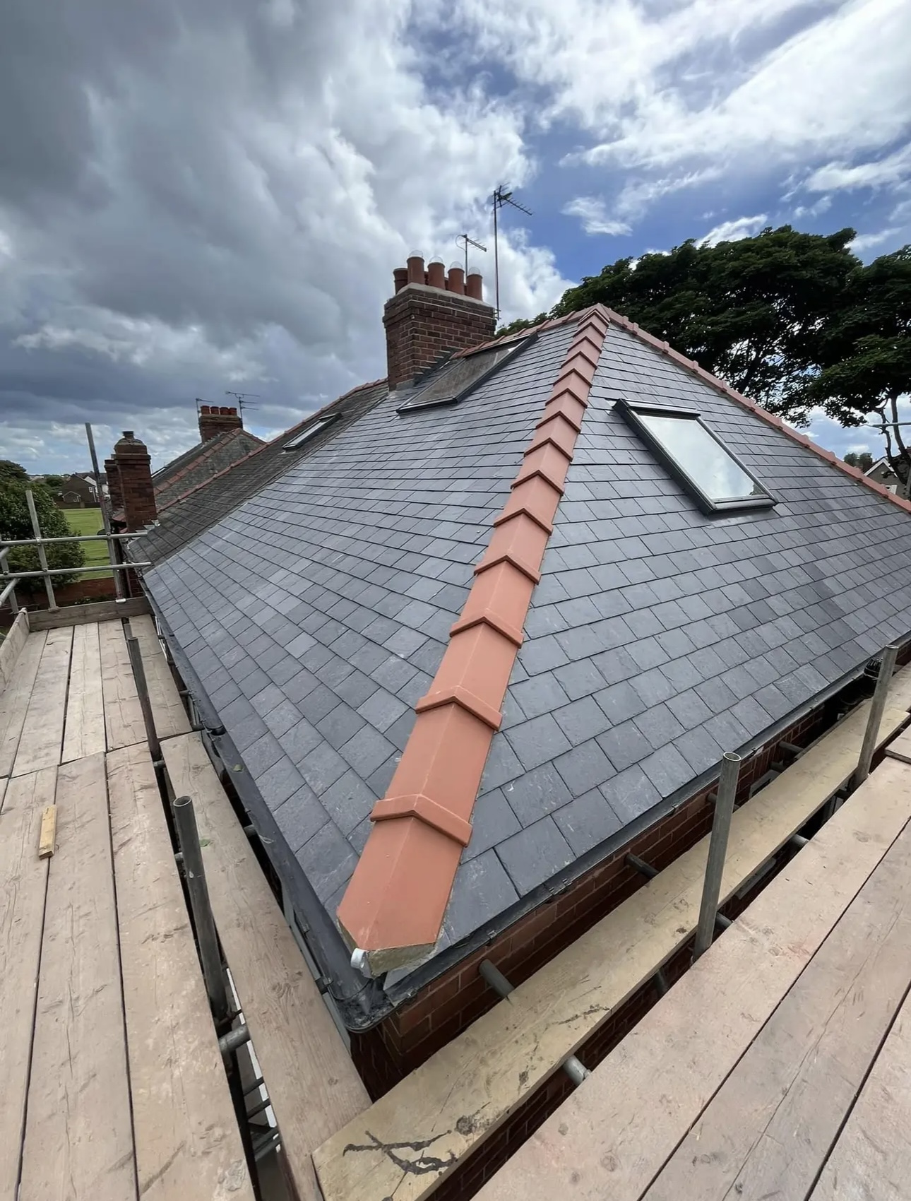 Grey slate roof finished with red ridge and hip tiles, and a rooflight in the slope