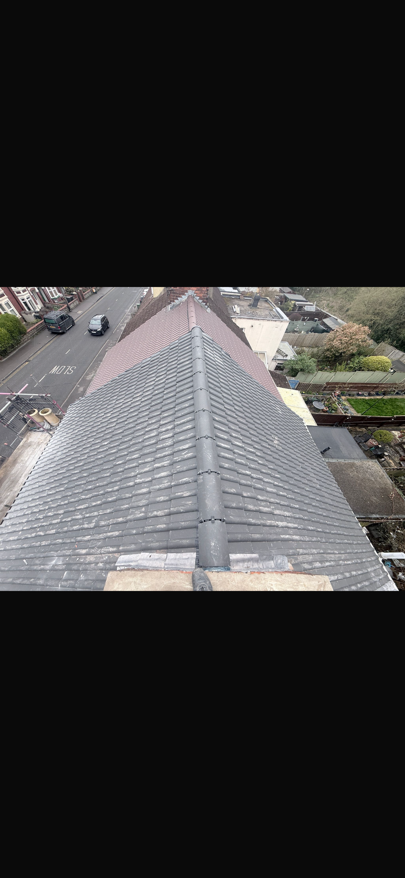 Grey tiled roof viewed from above with scaffolding and neat ridge lines