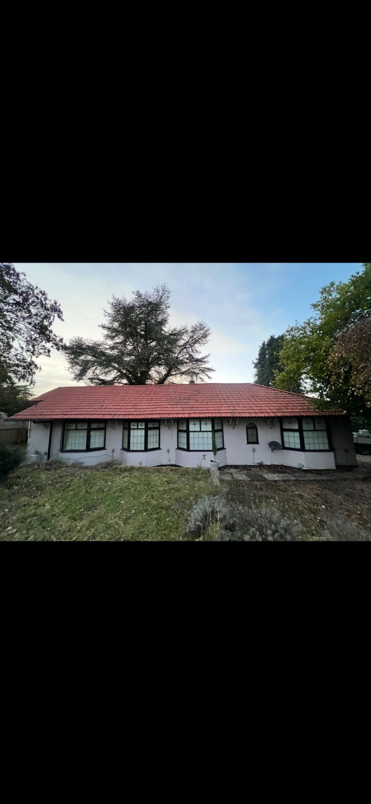 Long tiled bungalow roof seen from the garden on a bright day