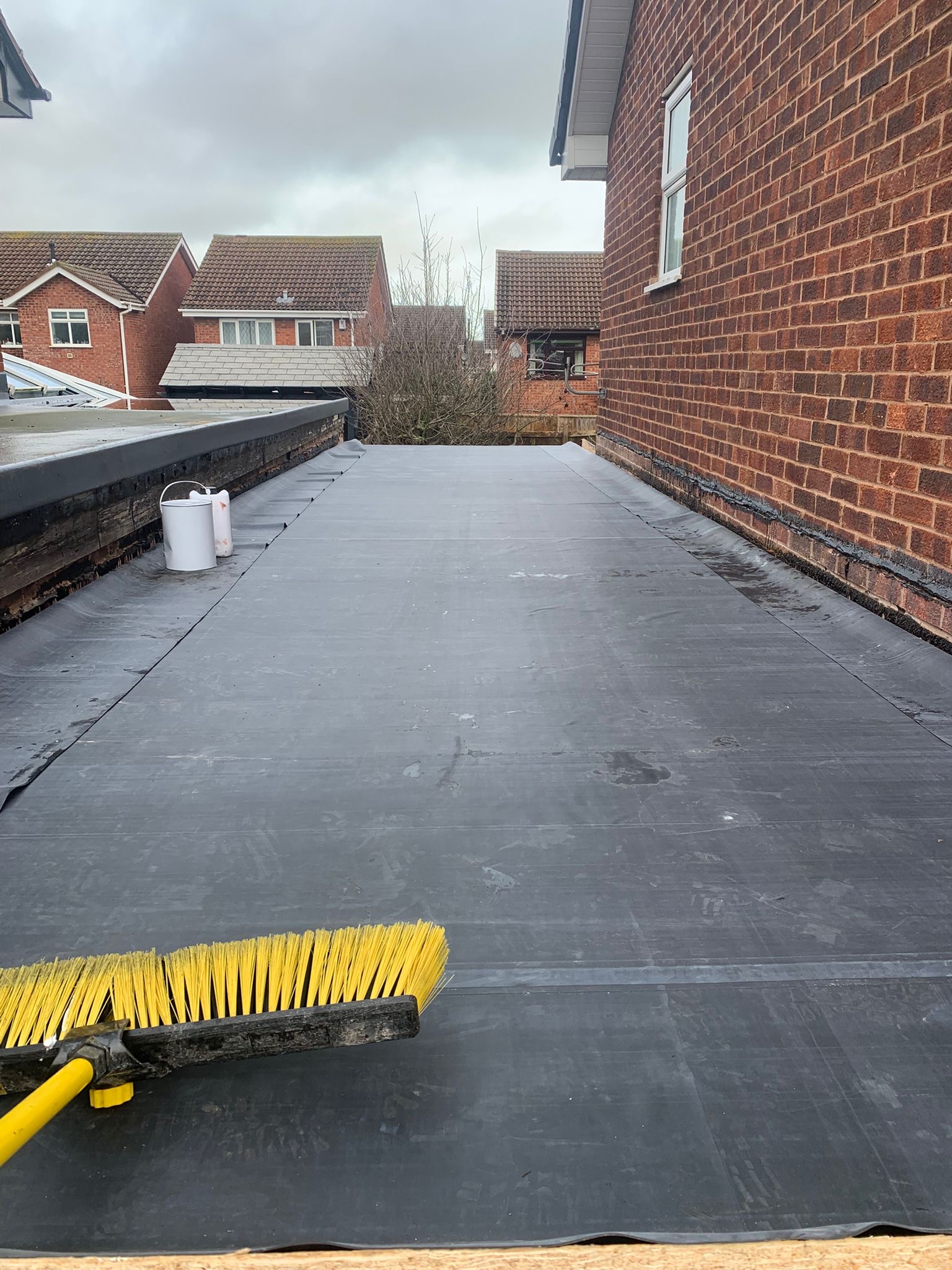 Finished grey flat roof beside a brick house
