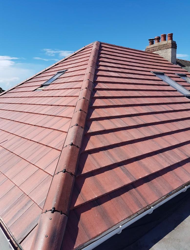 Finished red tiled hipped roof under a blue sky