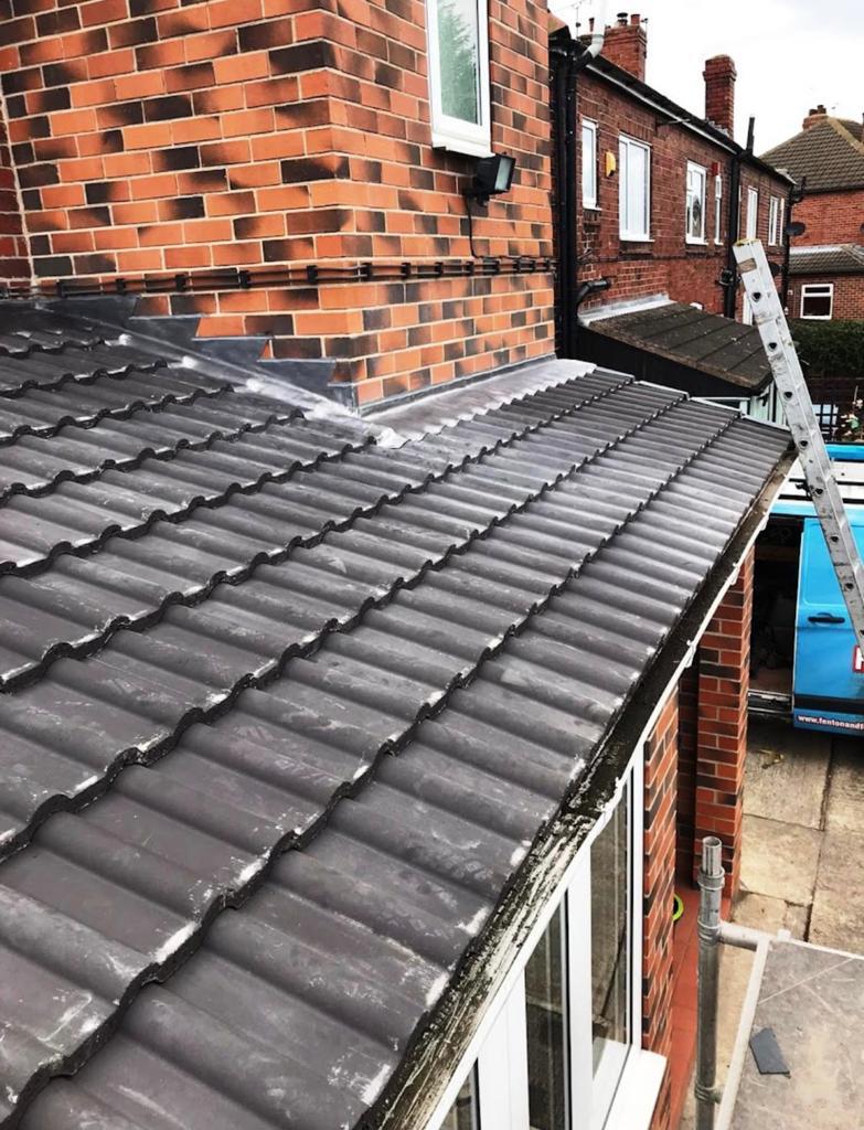 Small grey tiled roof fitted against a brick wall