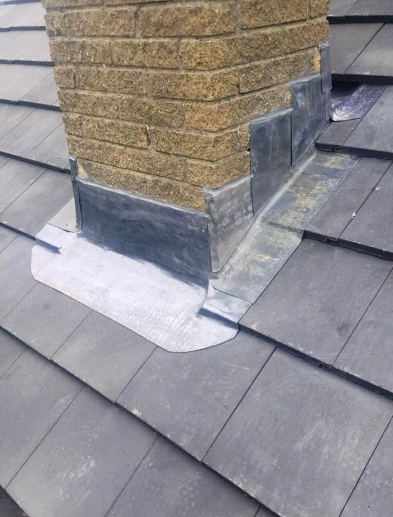 New lead flashing fitted around the base of a stone chimney