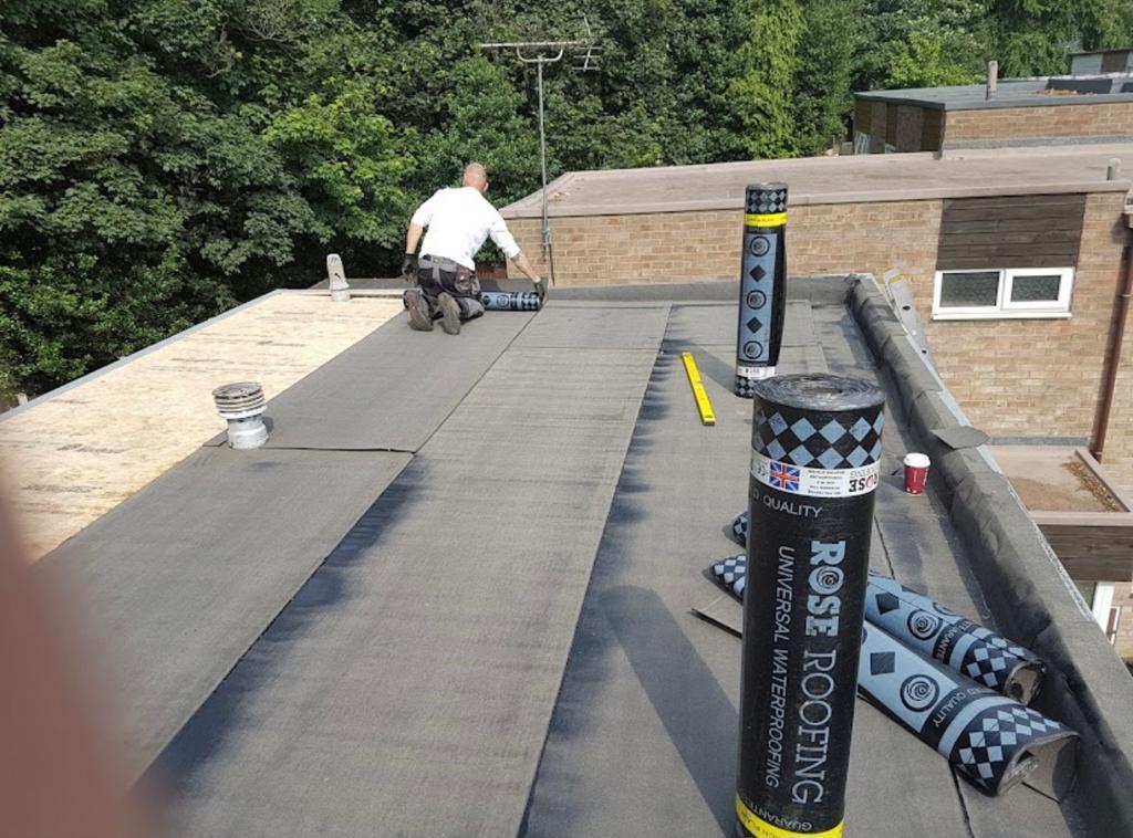 Roofing membrane being laid across a flat roof