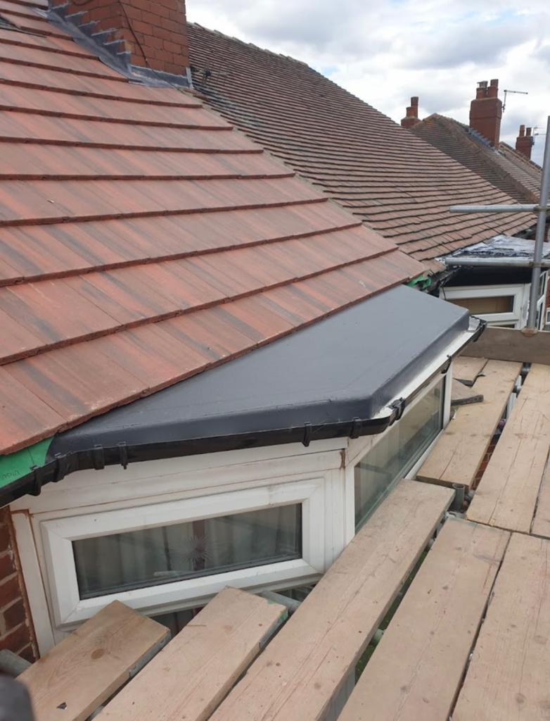 Dark fascia capping fitted along the edge of a red tiled roof