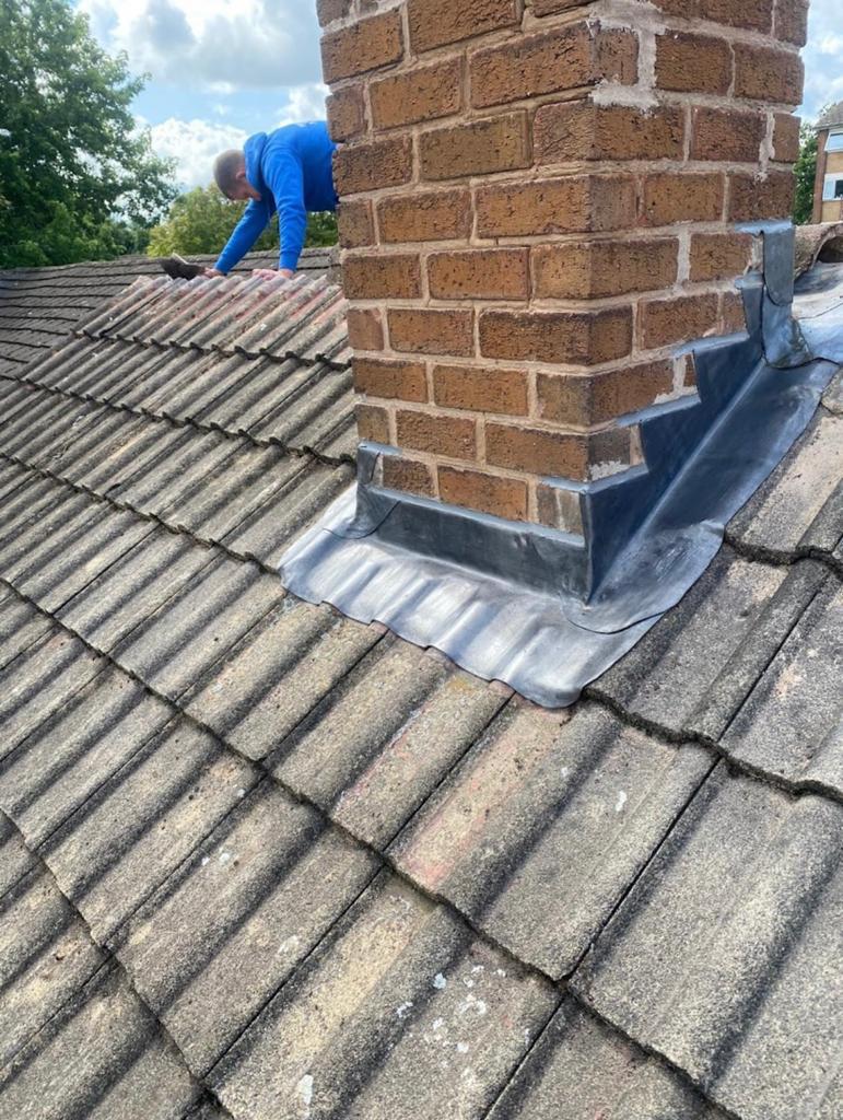 Lead flashing fitted around a brick chimney on a tiled roof