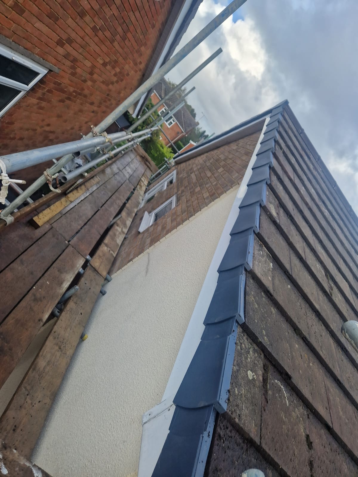 Dark verge tiles fitted above white exterior render