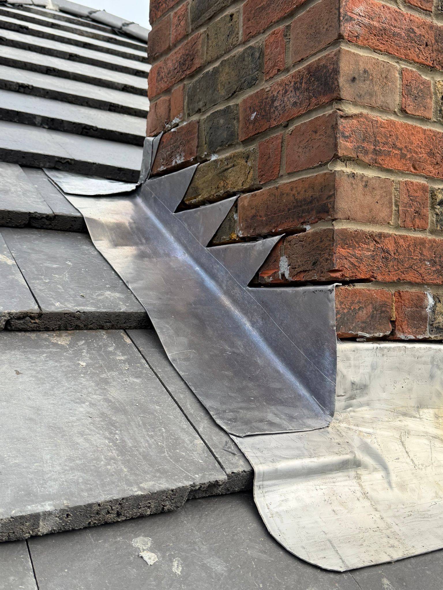 Detailed lead flashing fitted around a brick chimney