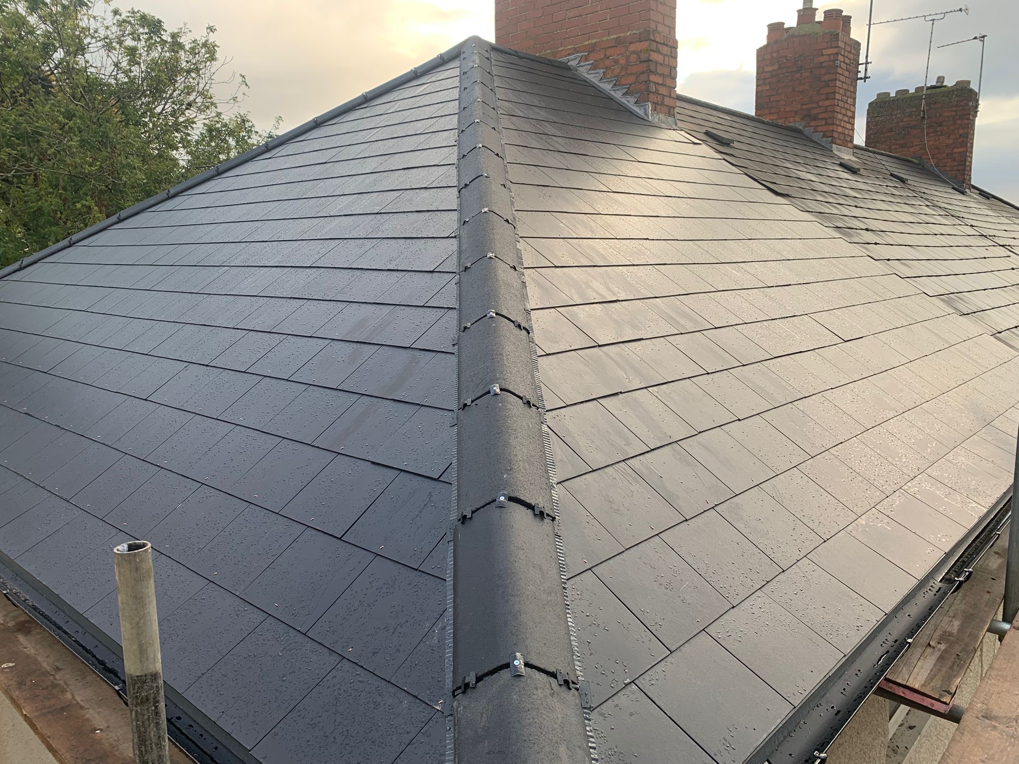Completed dark grey slate roof with a straight ridge
