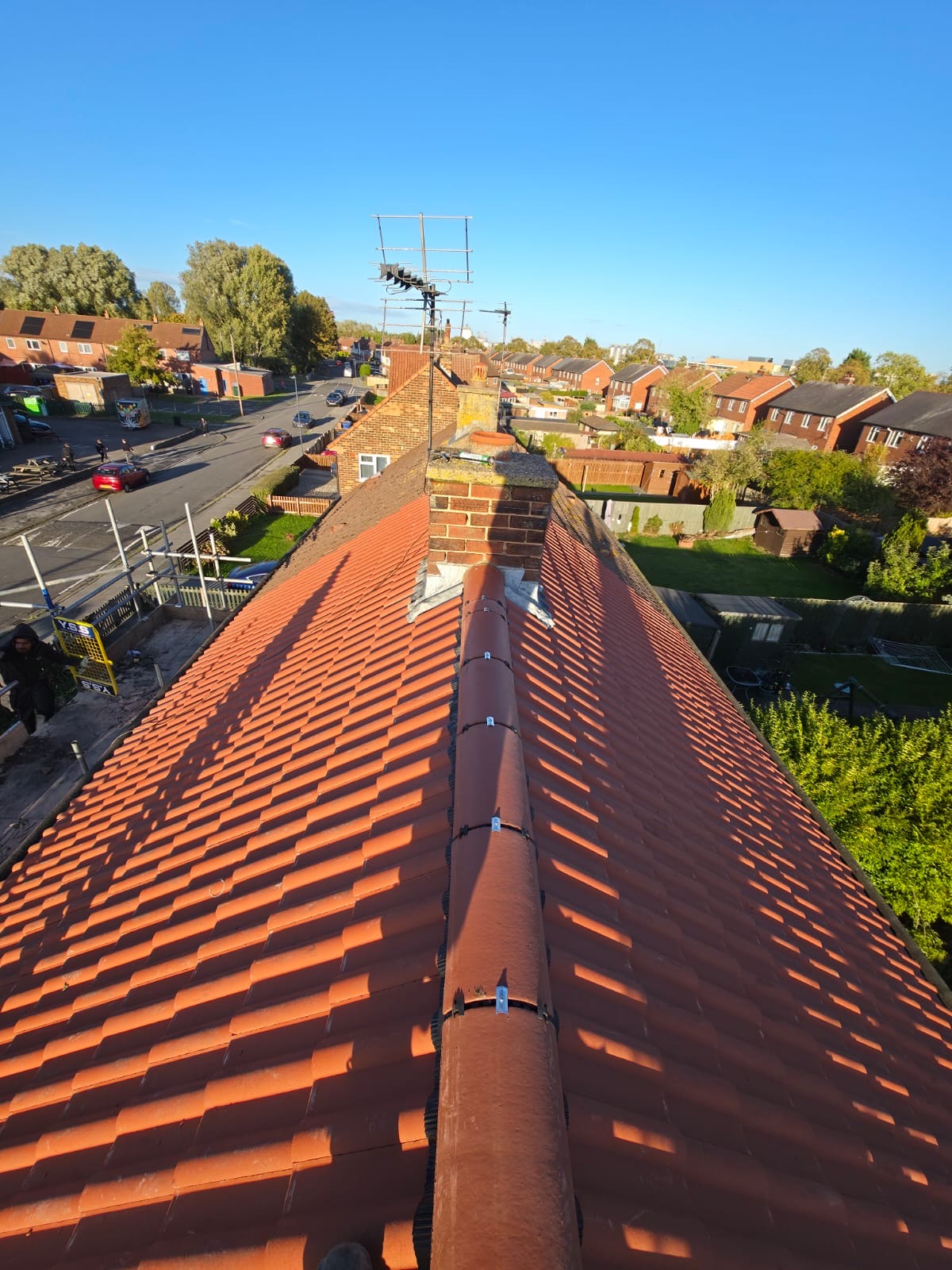 Finished red tiled roof with a neat ridge line, looking along a residential street