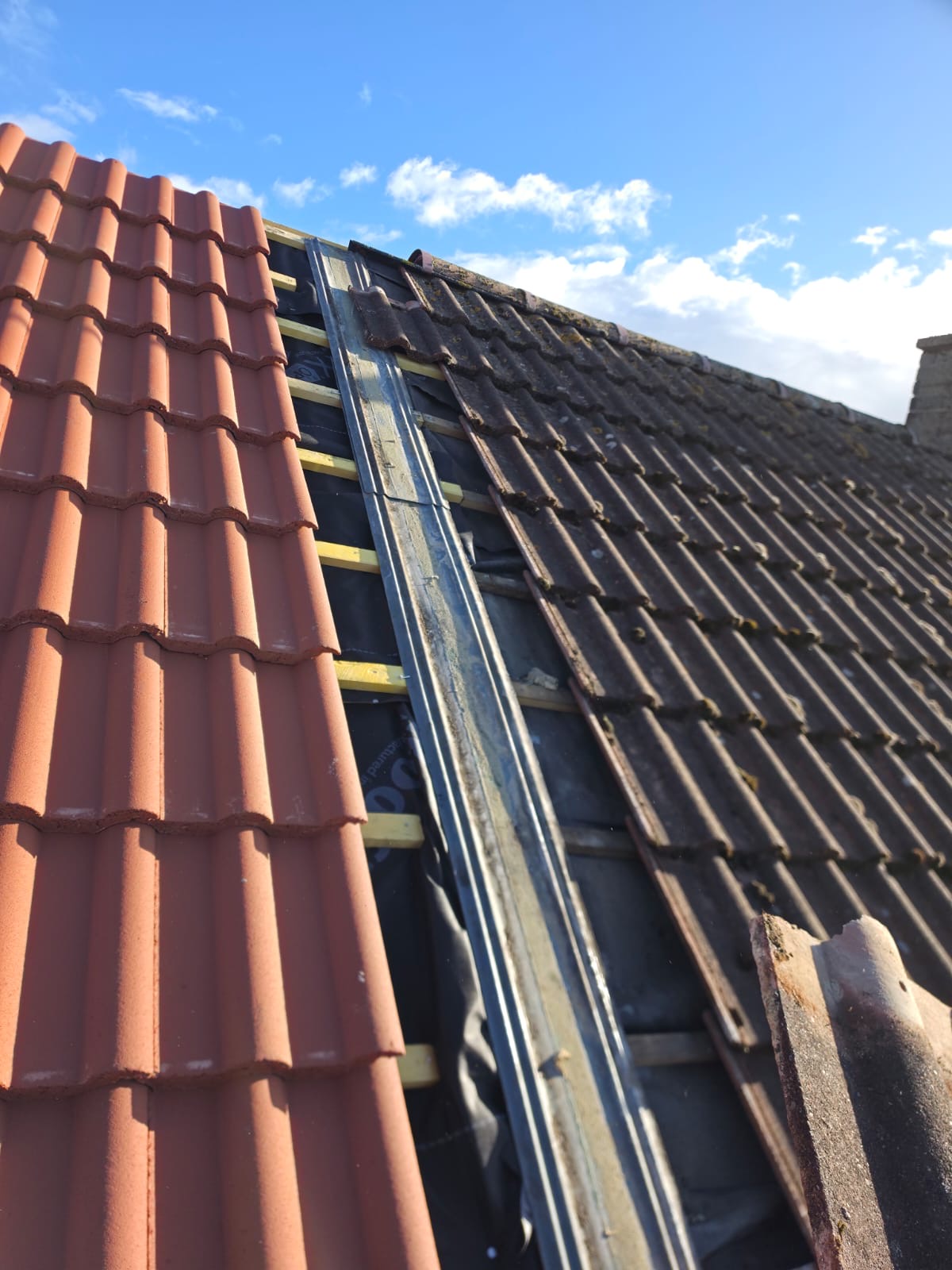 New metal valley being fitted between red tiles and dark grey tiles