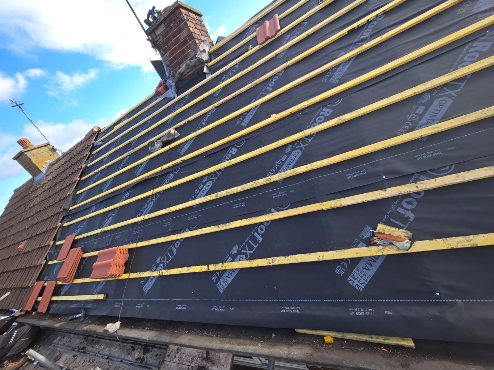 Wide view of a battened roof ready for tiling, with chimney stacks along the ridge