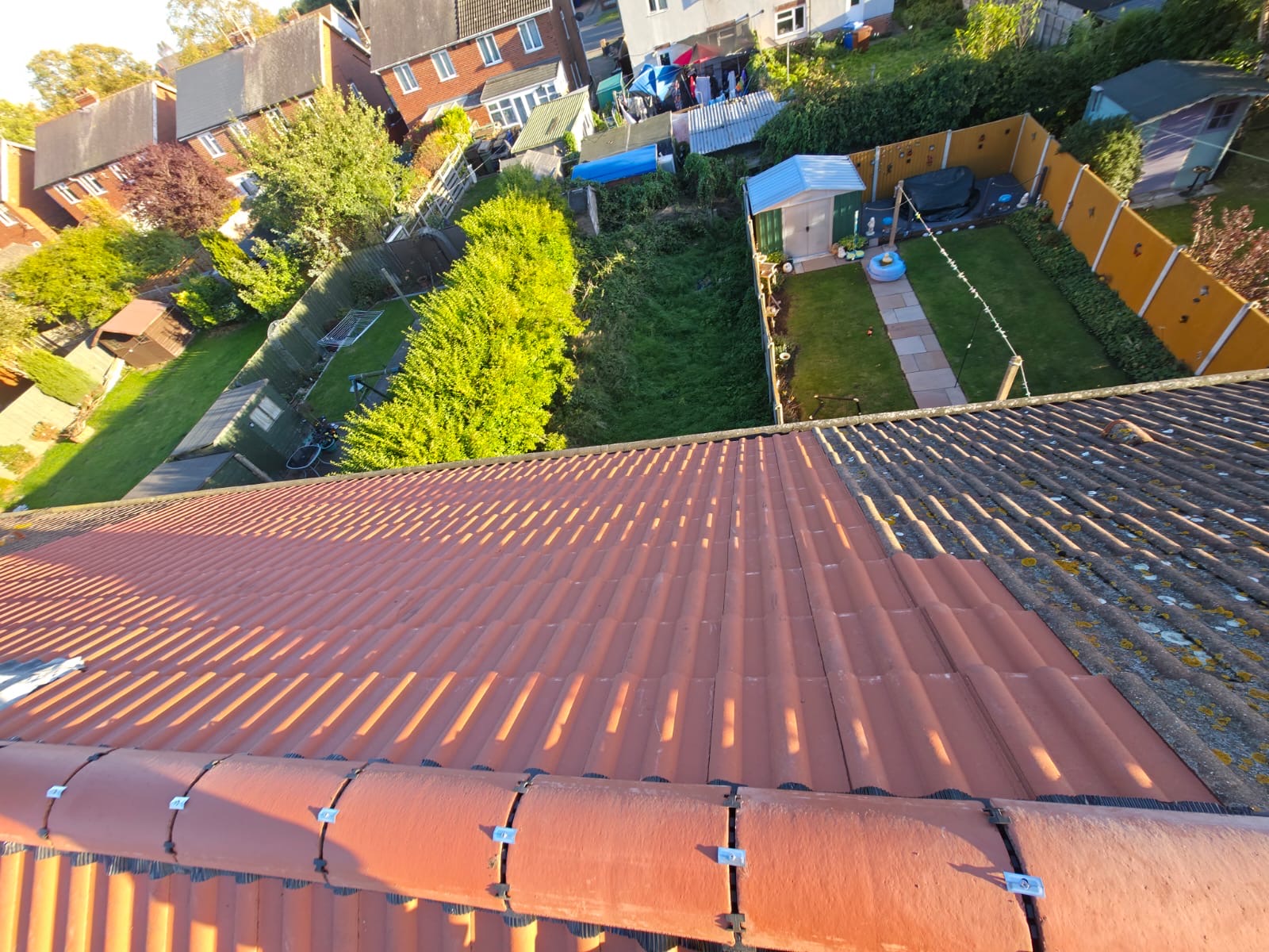 Completed red tiled roof seen from above, with gardens and houses behind