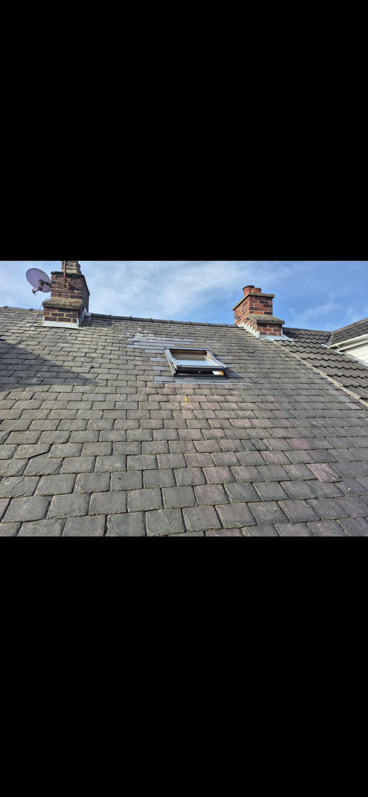 Pitched tiled roof seen from scaffolding, ridge line running along the top
