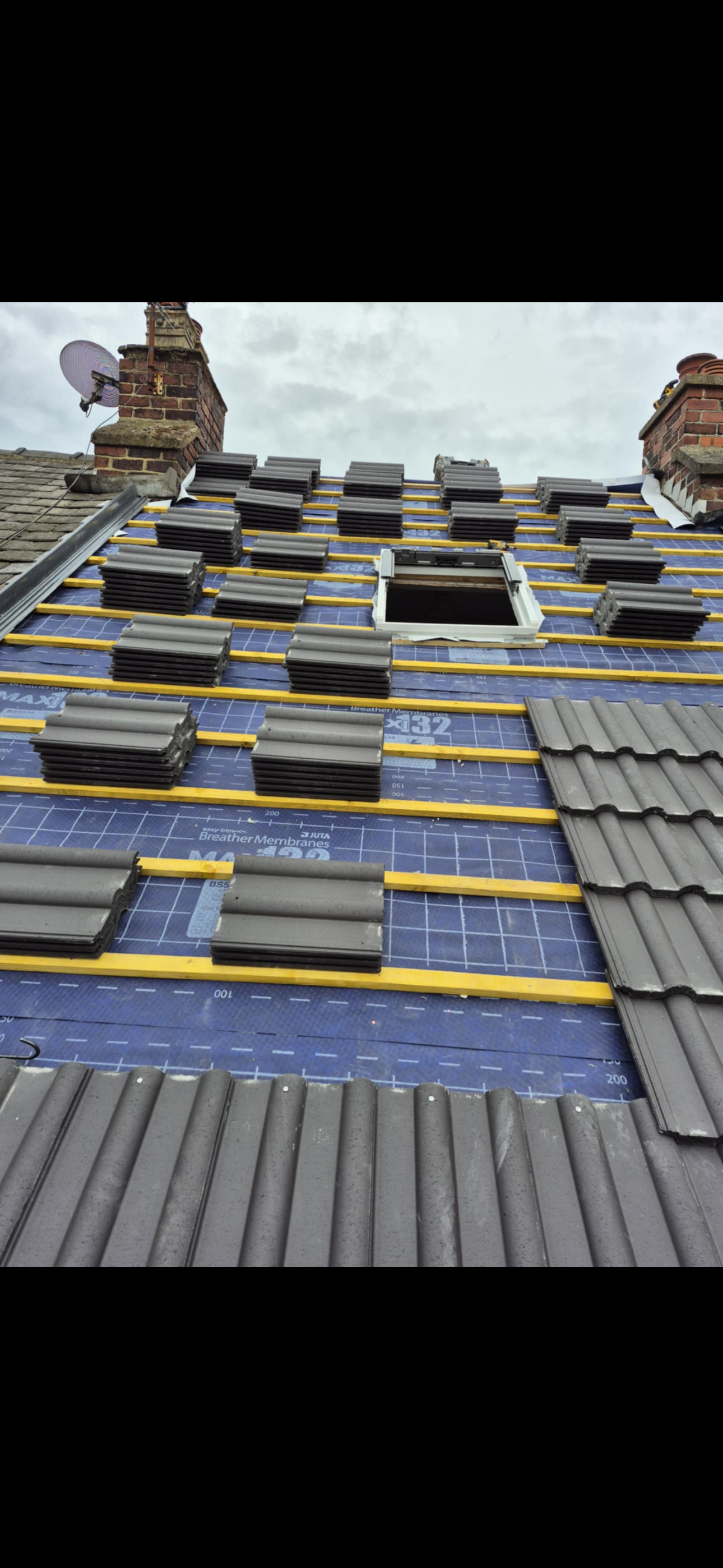 Roof slope with new tiles laid in even courses down to the gutter